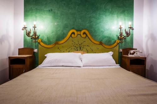 a bedroom with a large bed with a green wall at Palazzo Giunta - Porta Marina Ortigia in Siracusa