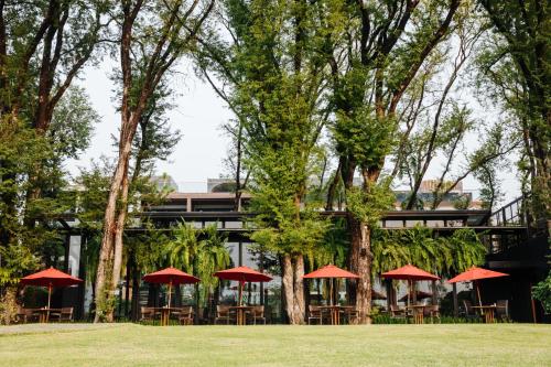 a group of tables with red umbrellas in front of a building at Cross Chiang Mai Riverside in Chiang Mai