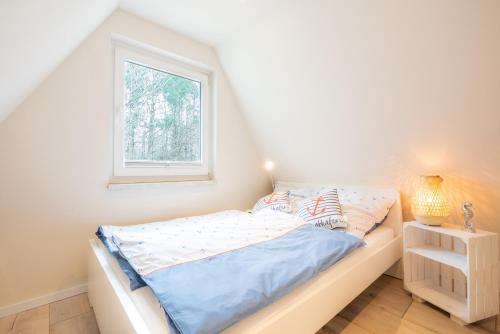 a white bedroom with a bed and a window at Luett Anna Ferienhaus auf Usedom in Quilitz