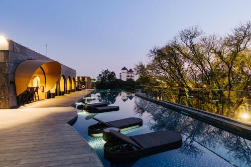 a hotel swimming pool with lounge chairs in the water at Cross Chiang Mai Riverside in Chiang Mai