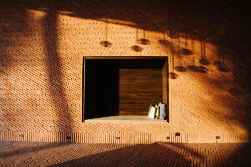 two cats sitting in a window in a brick wall at Cross Chiang Mai Riverside in Chiang Mai