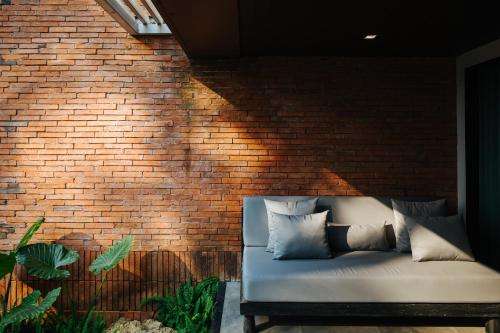 a couch sitting in front of a brick wall at Cross Chiang Mai Riverside in Chiang Mai