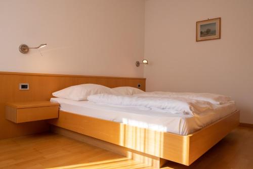1 dormitorio con cama de madera con sábanas blancas en Ferienwohung im Haus Texel I, en Rablà