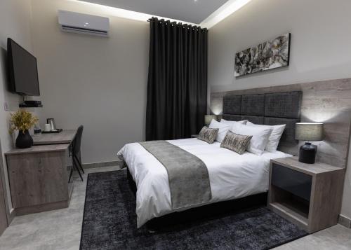 a bedroom with a bed and a desk and a television at Luxe Suites Boutique Hotel in Durban