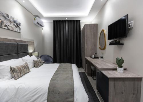 a bedroom with a bed and a desk and a television at Luxe Suites Boutique Hotel in Durban