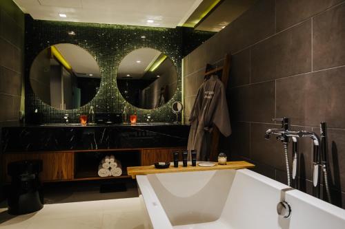 a bathroom with a white tub and a mirror at Cross Chiang Mai Riverside in Chiang Mai