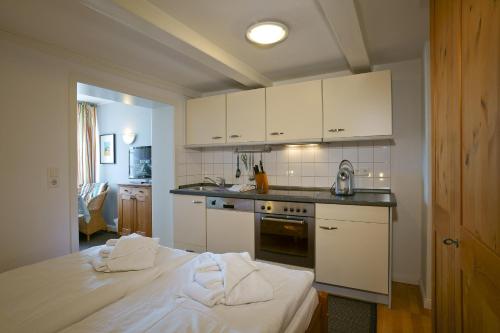 ヴィーク・アウフ・フェールにあるHaus Gud Hööb Whg 08の白いキャビネット付きのキッチン、ベッド1台が備わる客室です。