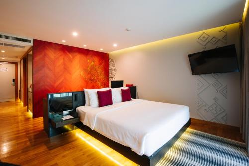 a bedroom with a bed and a flat screen tv at Cross Chiang Mai Riverside in Chiang Mai