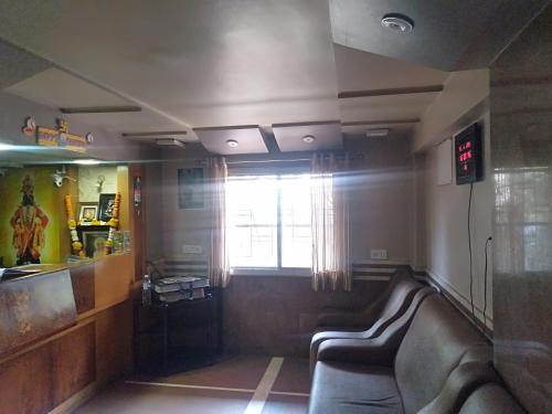 a waiting room with a couch and a window at Hotel Shiv Sangram in Ahmadnagar