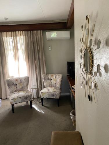 a living room with two chairs and a mirror at Oxford Lodge Vryheid in Vryheid