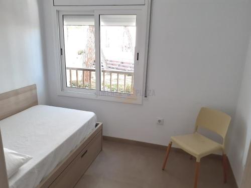 a bedroom with a bed and a chair and a window at Apartamentos Dins Mar Apto. 6 in Torredembarra