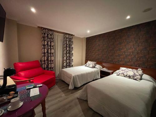 um quarto de hotel com duas camas e uma cadeira vermelha em La Siesta em Villamarciel