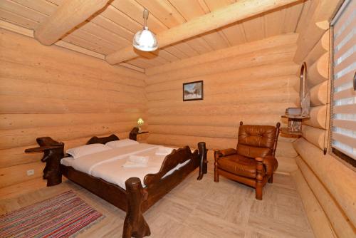 ein Schlafzimmer in einem Blockhaus mit einem Bett und einem Stuhl in der Unterkunft Casa Poligonului in Vatra Dornei