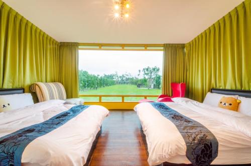 two beds in a room with a large window at 梅花湖-陽光屋民宿 in Dongshan