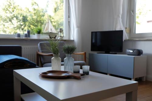ein Wohnzimmer mit einem weißen Tisch und einem TV in der Unterkunft Haus Doris - 19549 in Heiligenhafen