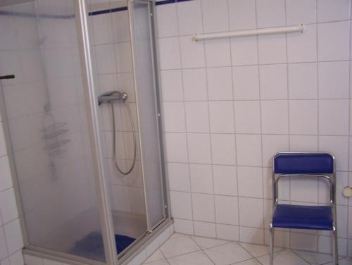 y baño con ducha y silla azul. en Ferienwohnung Mauer, Wohnung "A", en Heede