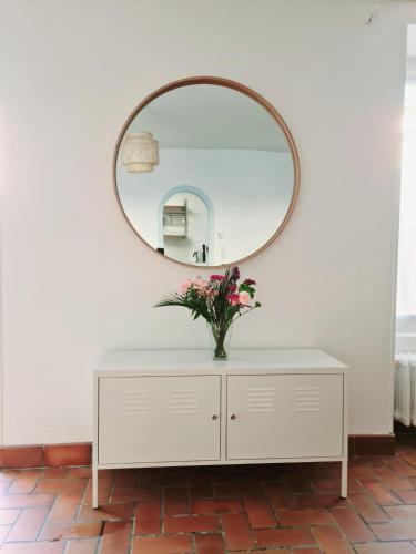 un miroir au-dessus d'une commode blanche avec un vase de fleurs dans l'établissement La maison d'Eglantine, 6 min du Puy du Fou, 4 chambres 10 couchages à St Malo-du-Bois,, à Saint-Malo-du-Bois