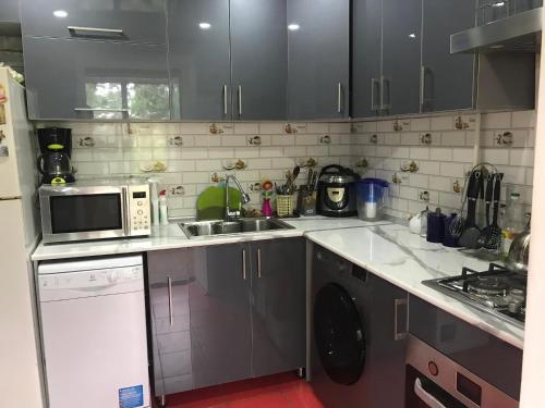 eine Küche mit einer Spüle und einer Mikrowelle in der Unterkunft Sweet Home in Taschkent