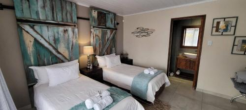 a hotel room with two beds and a bathroom at Rox and Sea Country Lodge in Langebaan