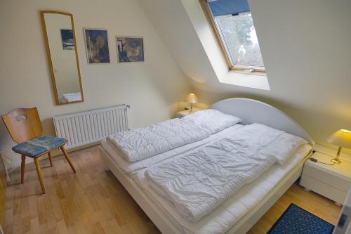 a bedroom with a white bed and a window at Kranich VIII, FW 39 in Zingst