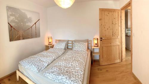 duas camas num quarto com uma porta e duas lâmpadas em Le Gîte du Midi em Fontainemelon