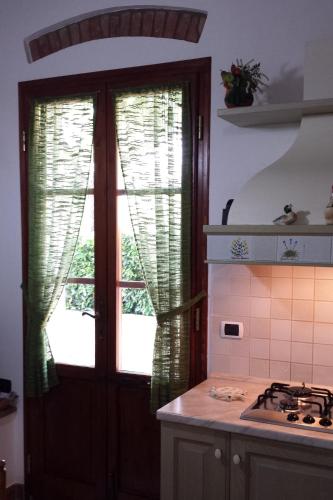 a kitchen with a stove and a window with curtains at Agriturismo Villino del Grillo in San Gimignano