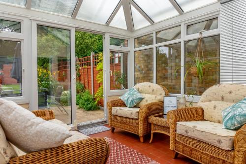 a conservatory with wicker chairs and wicker furniture at Red Cherry House in Watford