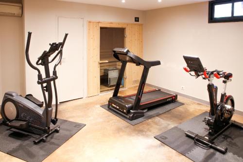 a gym with two treadmills and two exercise bikes at Hotel restaurant Spa Disini Montpellier Est, The Originals Relais in Castries