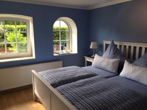 a blue bedroom with a bed and two windows at Stockrose in Schashagen