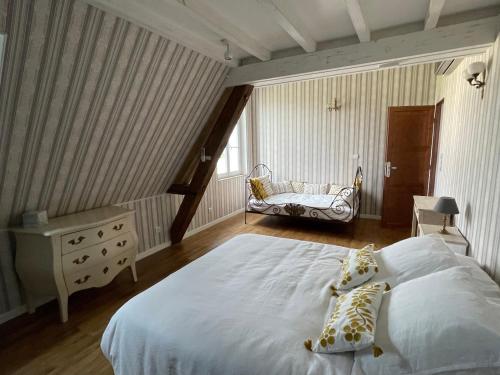 um quarto com uma grande cama branca e uma cadeira em La Métairie em Vernou-sur-Brenne
