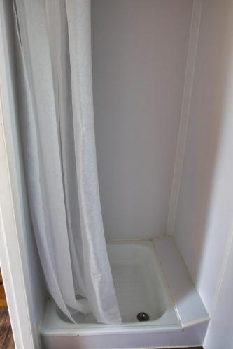 een douche met een wit douchegordijn in een kamer bij Finnenhaus 4 in Lübeck