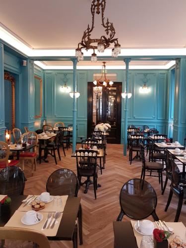 ein Esszimmer mit Tischen und Stühlen und einem Kronleuchter in der Unterkunft Hotel Peyris Opera in Paris