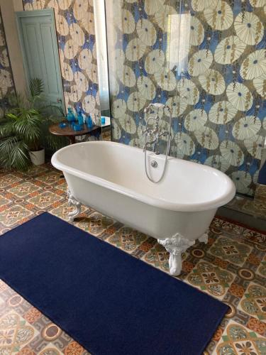 La salle de bains est pourvue d'une baignoire et d'un tapis bleu. dans l'établissement Chambre d'Hôte La Romaine, à Vaison-la-Romaine