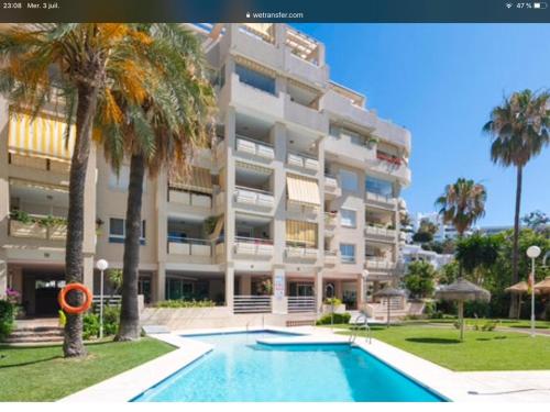 een groot appartementencomplex met een zwembad en palmbomen bij Apartamento entero en La Carihuela a 50 m de la playa in Torremolinos