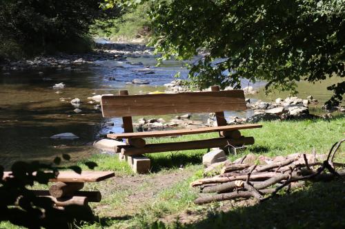 a wooden bench sitting next to a river at Beztroska Chata Bieszczady in Mchawa