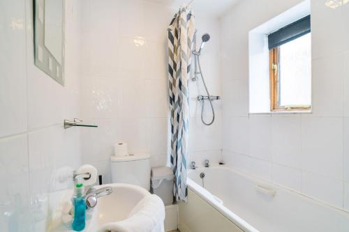 a white bathroom with a tub and a sink at The Dairy in Aberystwyth