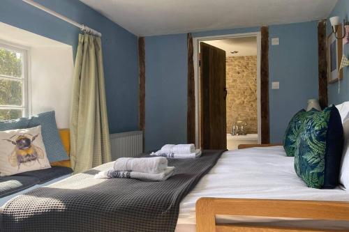 two beds in a bedroom with blue walls at The Explorers Rest - Cottage - Frome in Buckland Dinham