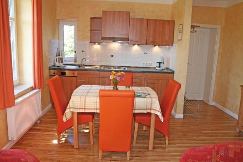 a kitchen with a table with orange chairs and a tableablish at Ferienhof Bisdorf "Sundbrücke" in Bisdorf