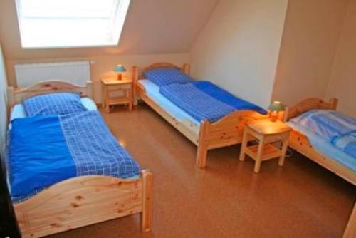 a room with three beds and two tables and a window at Ferienhof Bisdorf "Sundbrücke" in Bisdorf