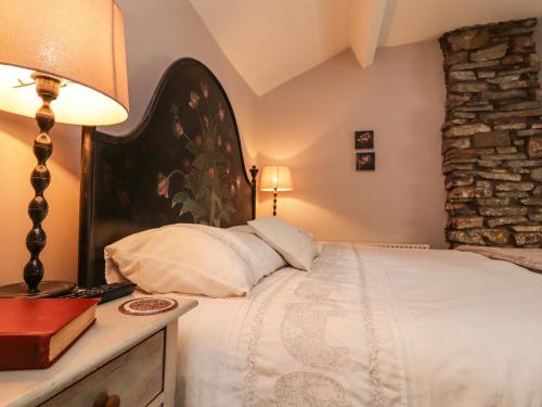 a bedroom with a bed with a lamp and a book at Duckdown in Clitheroe