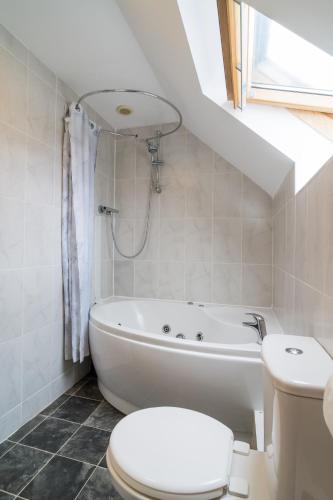 a white bathroom with a toilet and a bath tub at The Barn in Aberystwyth