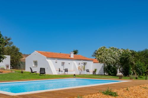 a villa with a swimming pool in front of a house at Casas Da Bica - Turismo Espaço Rural in Cercal