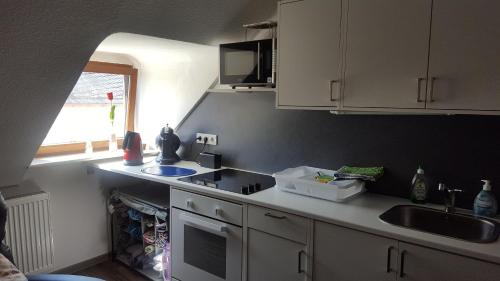 una cocina con armarios blancos y fregadero en Charmante Wohnung im Stadtkern, St Wendel, en Sankt Wendel