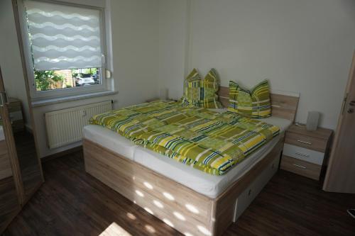 a bedroom with a bed with a yellow and green comforter at Am Sachsenstein - Zum Skispringer in Lauter