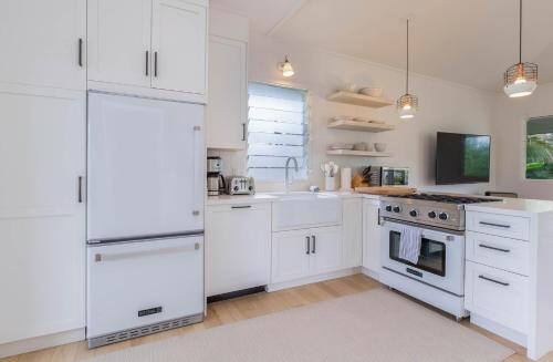 a white kitchen with white cabinets and appliances at Hanalei Beach House Estate home in Hanalei