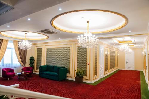 a living room with a green couch and chandeliers at Boutique Hotel Silk Way in Türkistan