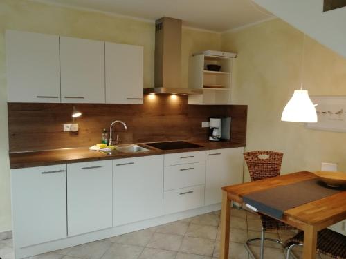 una cucina con armadi bianchi e tavolo in legno di Appartementhaus Süssling App 2 a Glowe