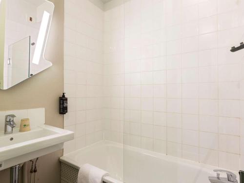 Baño blanco con bañera y lavamanos en Ibis Budget Bourgoin Jallieu Centre, en Bourgoin