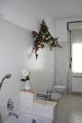 a bathroom with a sink and a toilet and a vase with flowers at City's House Guest House in Bergamo
