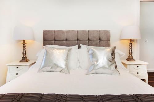 1 dormitorio con 1 cama blanca con almohadas y 2 lámparas en City Stay Apartments - Centro, en Milton Keynes
